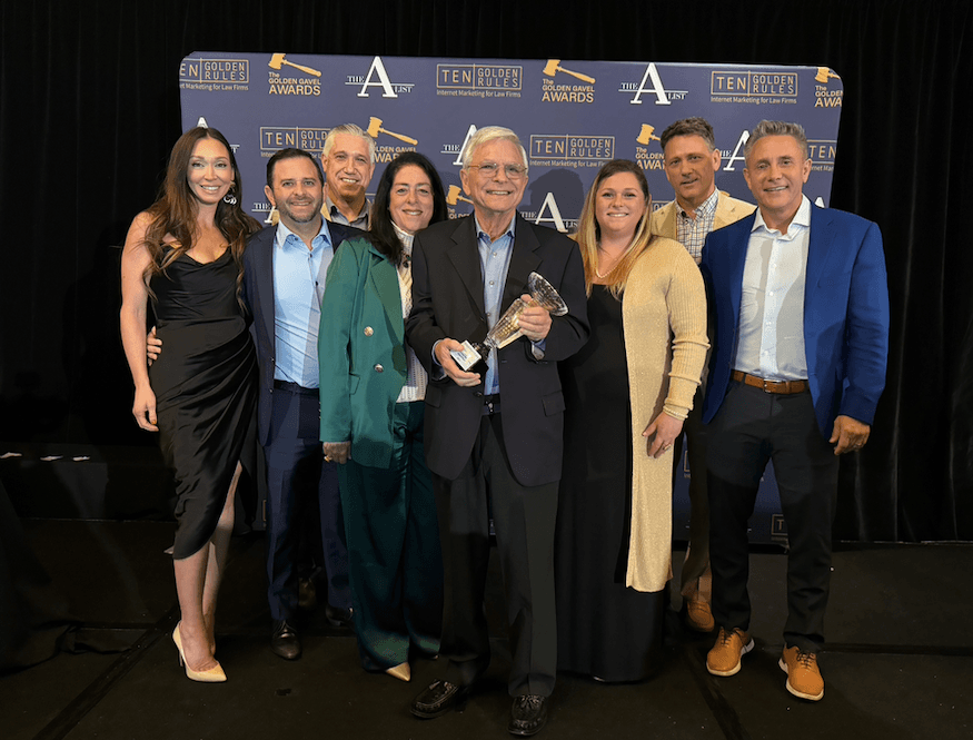 Richard Sackett holding the trophy at his 2024 Trial Lawyer Advertising Hall of Fame induction, surrounded by the Group Matrix team